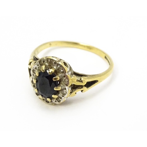 723 - A 9ct gold ring set with central sapphire bordered by diamonds. Ring size approx.  L 1/2