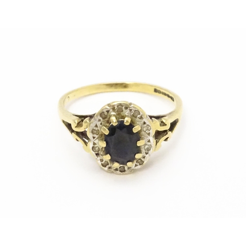 723 - A 9ct gold ring set with central sapphire bordered by diamonds. Ring size approx.  L 1/2