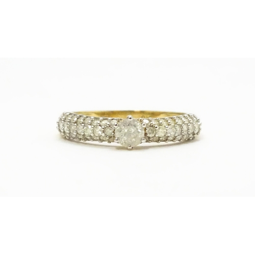 724 - A 9ct gold ring set with central diamond flanked by further diamonds to shoulders. Ring size approx.... 