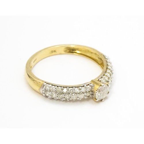 724 - A 9ct gold ring set with central diamond flanked by further diamonds to shoulders. Ring size approx.... 