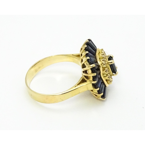 726 - A yellow metal cocktail ring set with central sapphire blue coloured stone bordered by diamonds and ... 