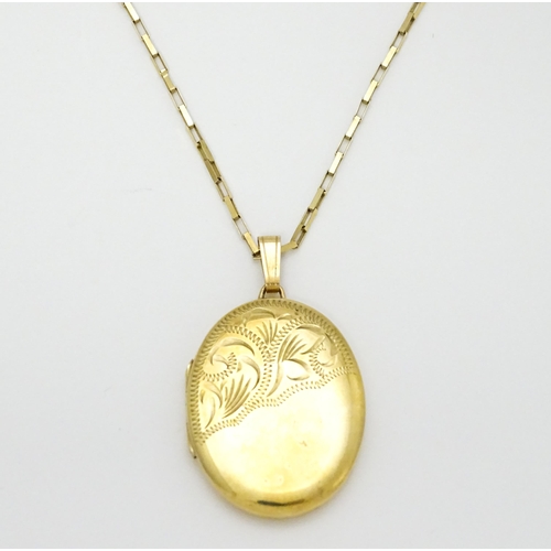 746 - A 9ct gold locket with engraved decoration, on a 9ct gold chain. Locket approx. 1 1/8