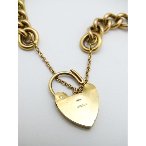 747 - A 9ct gold bracelet with padlock clasp and set with two 9ct gold charms, one a wishing well, the oth... 