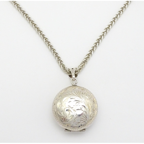 758 - A silver pendant of locket form with engraved foliate decoration. With a silver chain. Locket approx... 