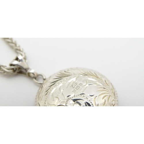 758 - A silver pendant of locket form with engraved foliate decoration. With a silver chain. Locket approx... 