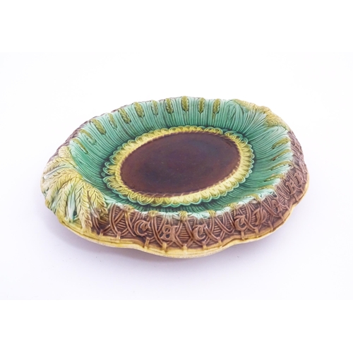 150A - A Victorian majolica bread plate, the inner rim decorated with wheat sheaves, the outer edge bearing... 