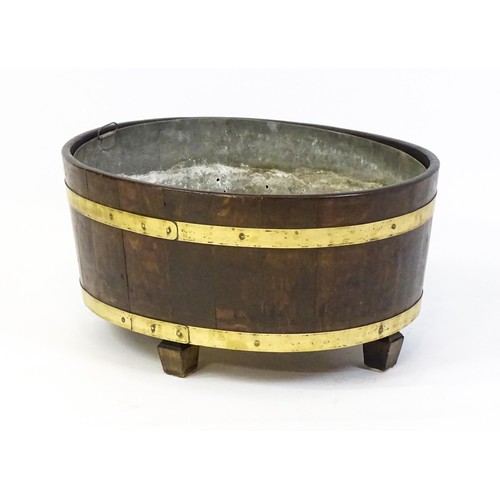 1608 - A late Georgian oak wine cooler / cellarette with a coopered and brass strapped frame and raised on ... 