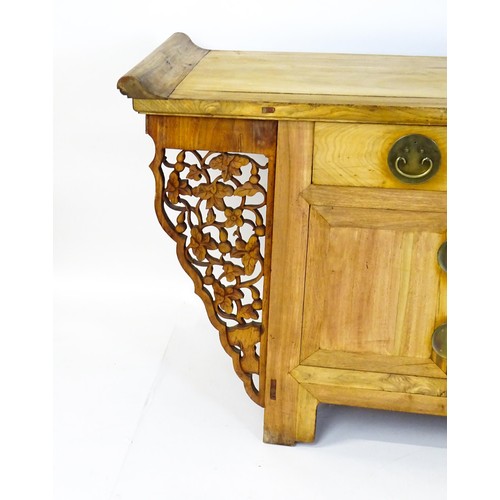 1659 - A mid 20thC oriental sideboard with a planked top, shaped ends and pierced brackets to either side w... 