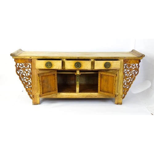 1659 - A mid 20thC oriental sideboard with a planked top, shaped ends and pierced brackets to either side w... 