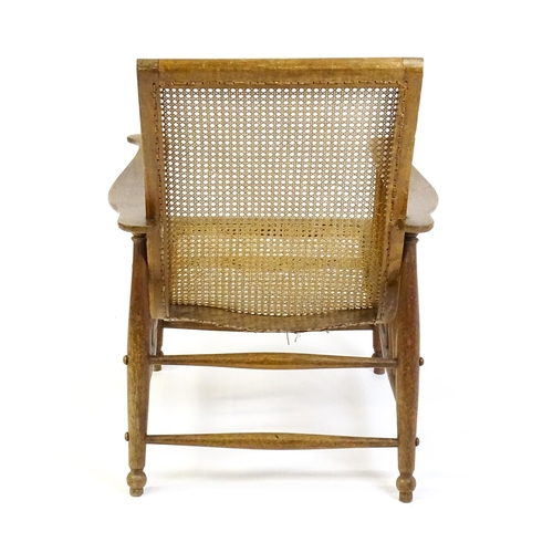 1694 - An Arts & Crafts bergère chair with a caned backrest and seat, the shaped arms supported by turned t... 