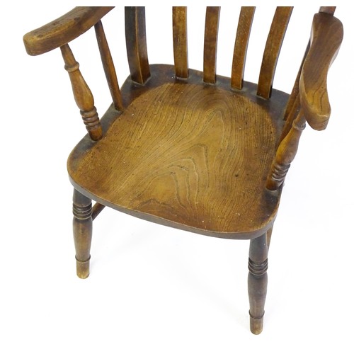 1698 - A late 19thC lathe back Windsor chair with swept arms above a shaped elm seat and raised on turned t... 