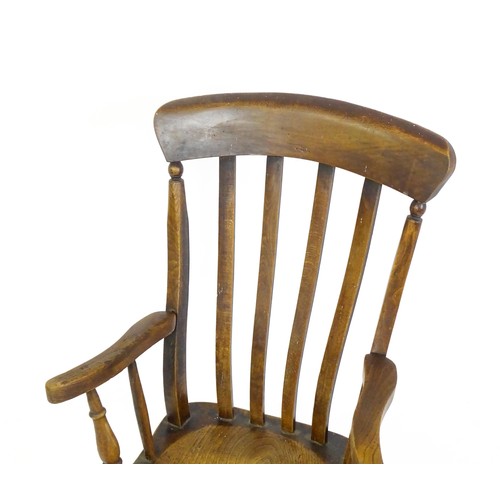 1698 - A late 19thC lathe back Windsor chair with swept arms above a shaped elm seat and raised on turned t... 