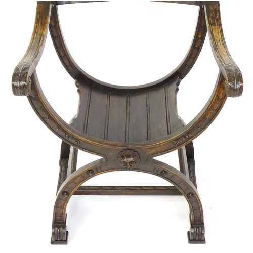 1703 - Two late 19thC / early 20thC Savonarola chairs, the uprights of scrolled form with carved mask detai... 