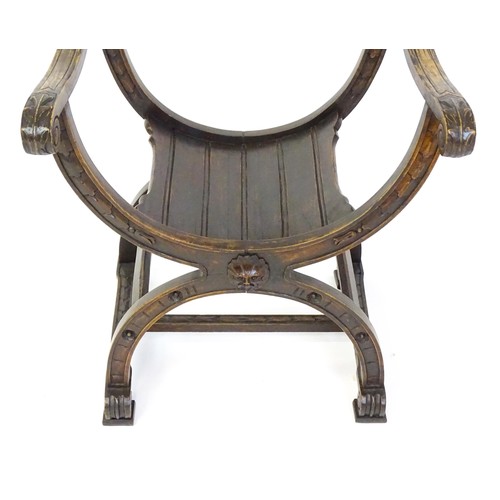 1703 - Two late 19thC / early 20thC Savonarola chairs, the uprights of scrolled form with carved mask detai... 