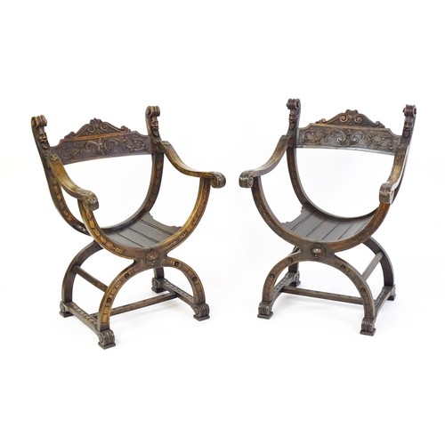 1703 - Two late 19thC / early 20thC Savonarola chairs, the uprights of scrolled form with carved mask detai... 