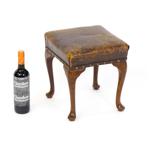 1718 - A late 19thC / early 20thC oak footstool with a leather upholstered stool and raised on four cabriol... 