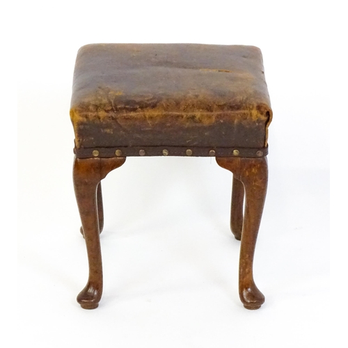 1718 - A late 19thC / early 20thC oak footstool with a leather upholstered stool and raised on four cabriol... 