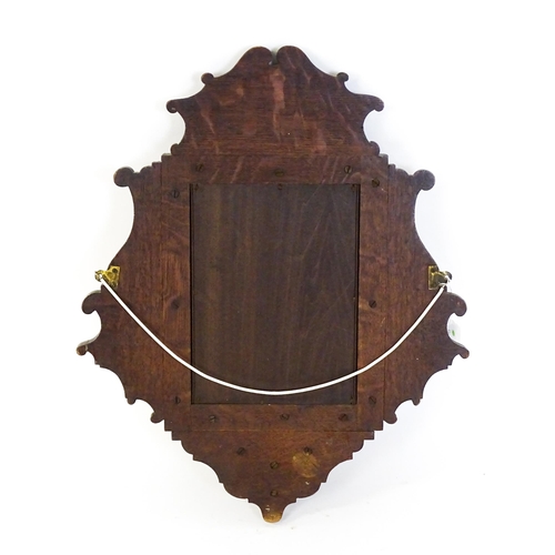 1724 - An Edwardian oak shield shaped mirror with carved egg and dart detailing and a small display shelf. ... 