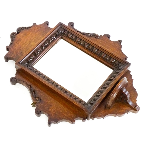 1724 - An Edwardian oak shield shaped mirror with carved egg and dart detailing and a small display shelf. ... 