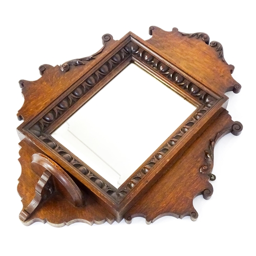 1724 - An Edwardian oak shield shaped mirror with carved egg and dart detailing and a small display shelf. ... 