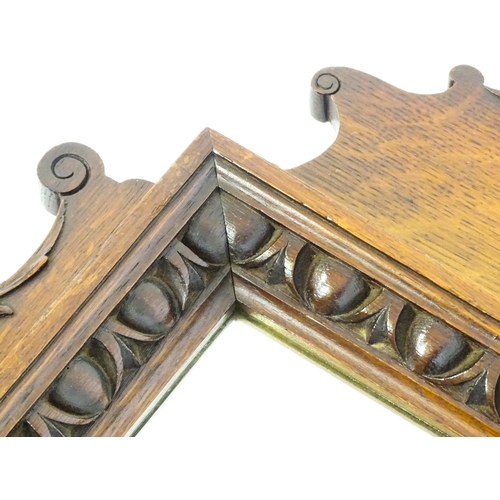 1724 - An Edwardian oak shield shaped mirror with carved egg and dart detailing and a small display shelf. ... 