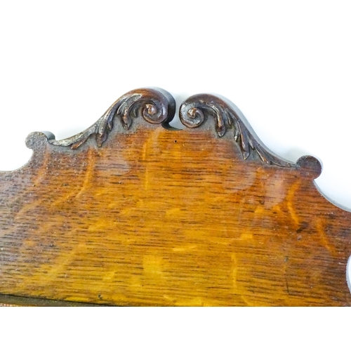 1724 - An Edwardian oak shield shaped mirror with carved egg and dart detailing and a small display shelf. ... 