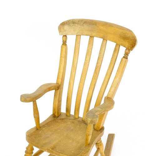 1742 - A mid 20thC child's lathe back Windsor rocking chair, with swept arms, a shaped seat and raised on f... 