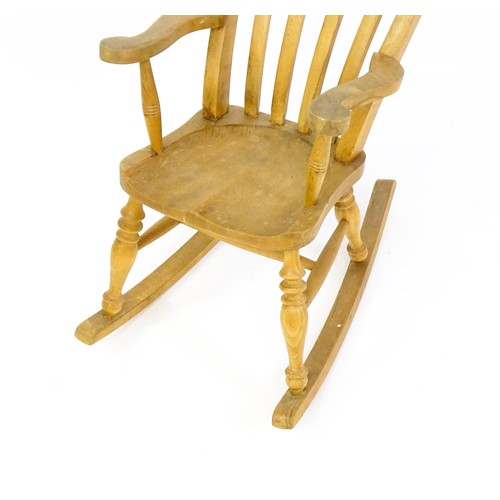 1742 - A mid 20thC child's lathe back Windsor rocking chair, with swept arms, a shaped seat and raised on f... 