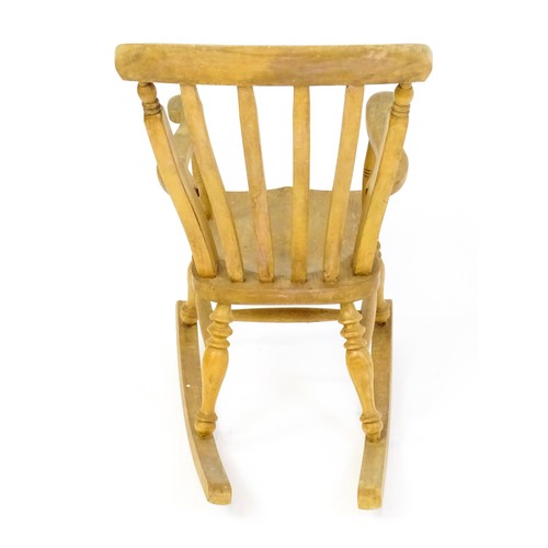 1742 - A mid 20thC child's lathe back Windsor rocking chair, with swept arms, a shaped seat and raised on f... 