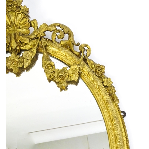 1541 - A 19thC giltwood and gesso oval mirror surmounted by a carved shell amongst bow and swag detailing a... 
