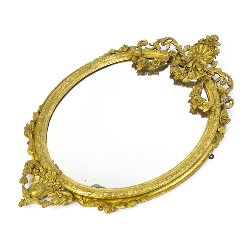 1541 - A 19thC giltwood and gesso oval mirror surmounted by a carved shell amongst bow and swag detailing a... 