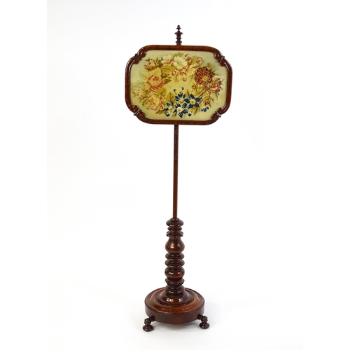 1550 - A mid 19thC mahogany pole screen, with a glazed adjustable screen having a needlework centre and re-... 