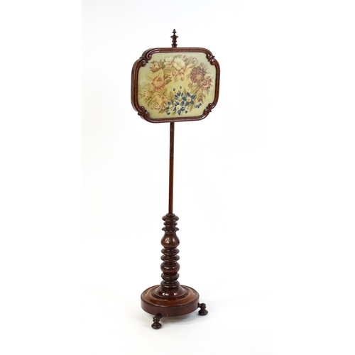 1550 - A mid 19thC mahogany pole screen, with a glazed adjustable screen having a needlework centre and re-... 