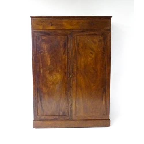 1554 - An early 19thC mahogany linen press with a single long drawer having floral carved knobs above two p... 