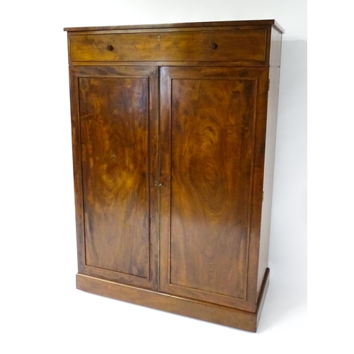 1554 - An early 19thC mahogany linen press with a single long drawer having floral carved knobs above two p... 