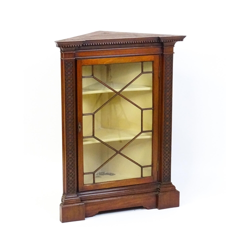 1555 - An early 19thC mahogany corner cupboard with a dentil moulded frieze and quatrefoil blink fretwork c... 