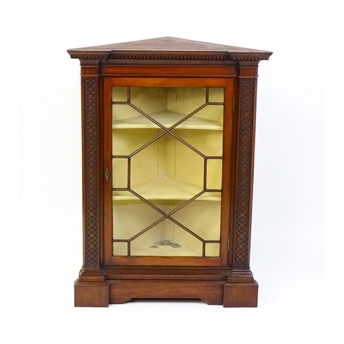 1555 - An early 19thC mahogany corner cupboard with a dentil moulded frieze and quatrefoil blink fretwork c... 