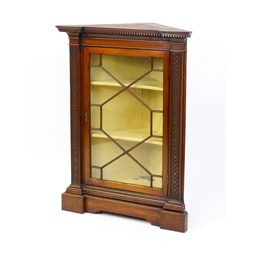 1555 - An early 19thC mahogany corner cupboard with a dentil moulded frieze and quatrefoil blink fretwork c... 