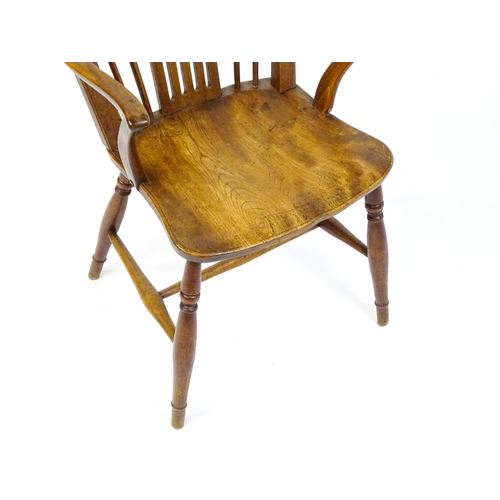 1558 - A late Georgian Windsor chair with a fanned back splat, a shaped seat and raised on turned tapering ... 