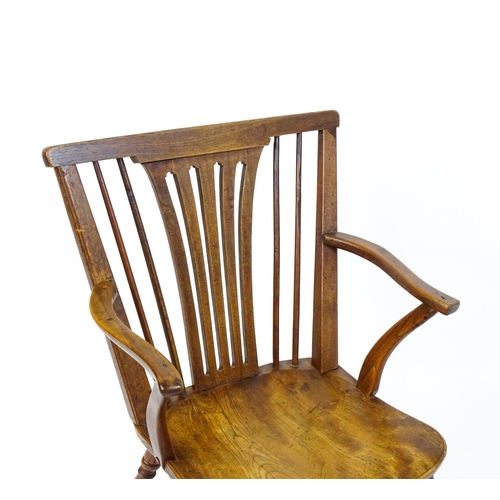 1558 - A late Georgian Windsor chair with a fanned back splat, a shaped seat and raised on turned tapering ... 