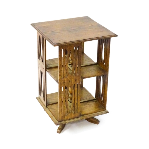 1563 - A late 19thC / early 20thC oak revolving bookcase, each side having pierced slats and four small she... 