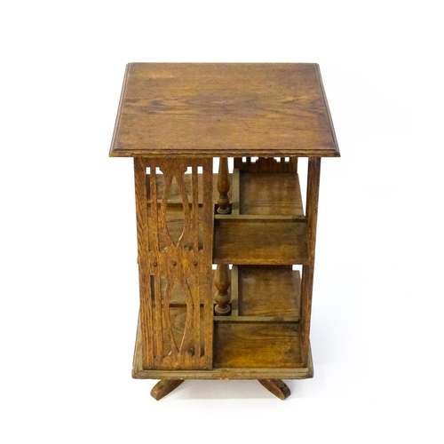 1563 - A late 19thC / early 20thC oak revolving bookcase, each side having pierced slats and four small she... 
