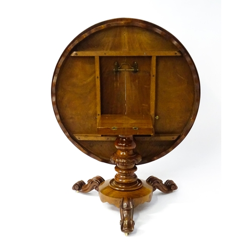 1564 - A 19thC mahogany tilt top breakfast table with a carved frieze above a turned and carved pedestal ba... 