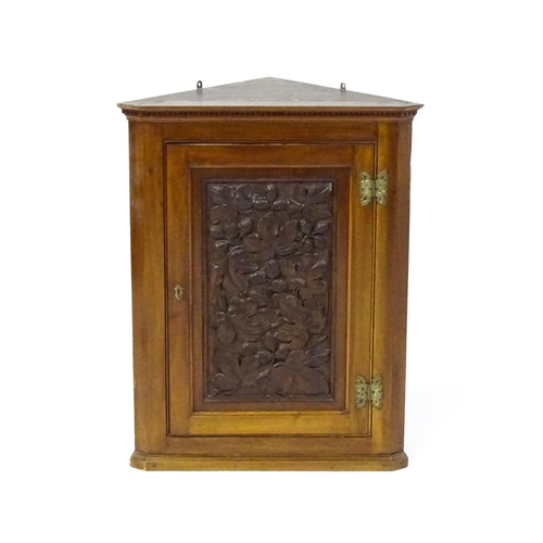 1570 - An Aesthetic period walnut corner cupboard with a carved door showing carved floral decoration. 22