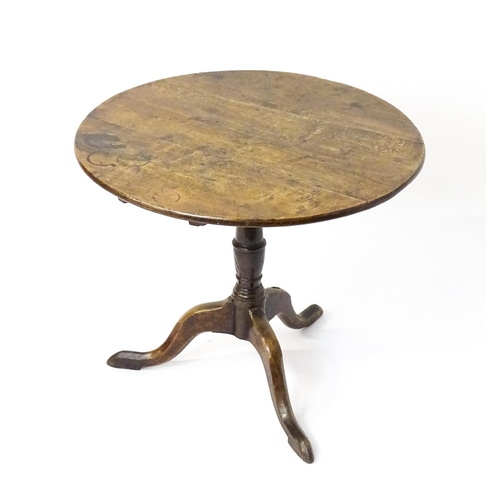 1577 - A mid / late 18thC oak tilt top occasional table with a circular planked top above a turned pedestal... 