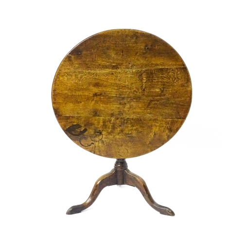 1577 - A mid / late 18thC oak tilt top occasional table with a circular planked top above a turned pedestal... 