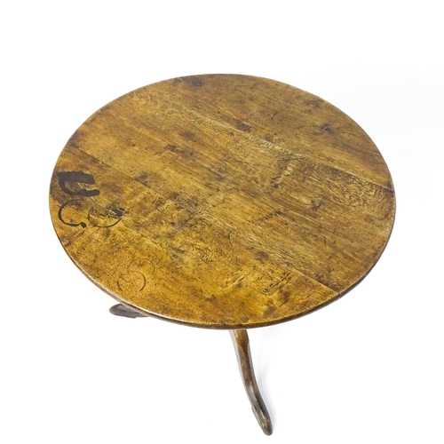 1577 - A mid / late 18thC oak tilt top occasional table with a circular planked top above a turned pedestal... 