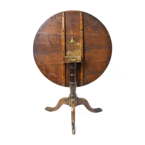 1577 - A mid / late 18thC oak tilt top occasional table with a circular planked top above a turned pedestal... 