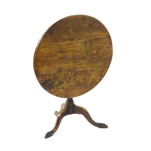 1577 - A mid / late 18thC oak tilt top occasional table with a circular planked top above a turned pedestal... 