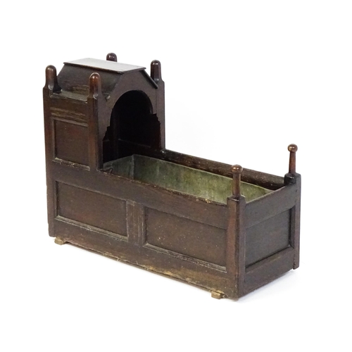 1586 - A mid / late 18thC oak cradle / crib / wine cooler with turned posts and a panelled structure, the i... 